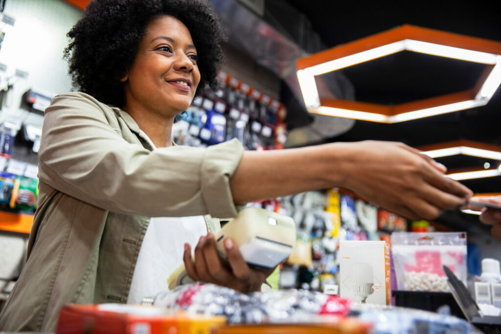 African American hardware shop worker charging on credit card to customer