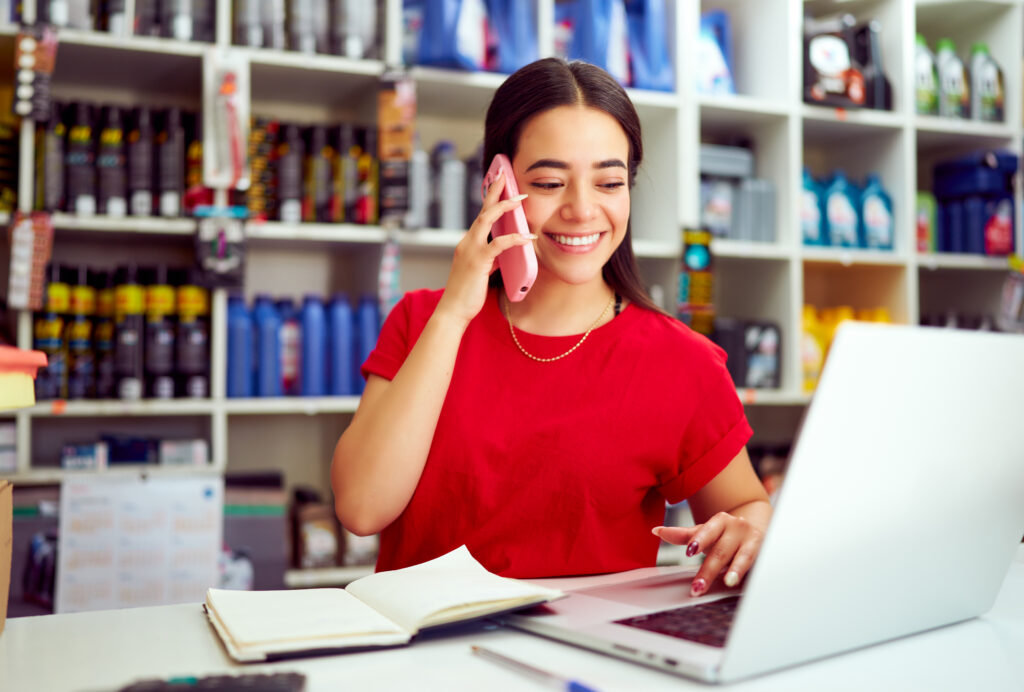 Saleswoman taking orders by phone and entering data into laptop in auto parts store